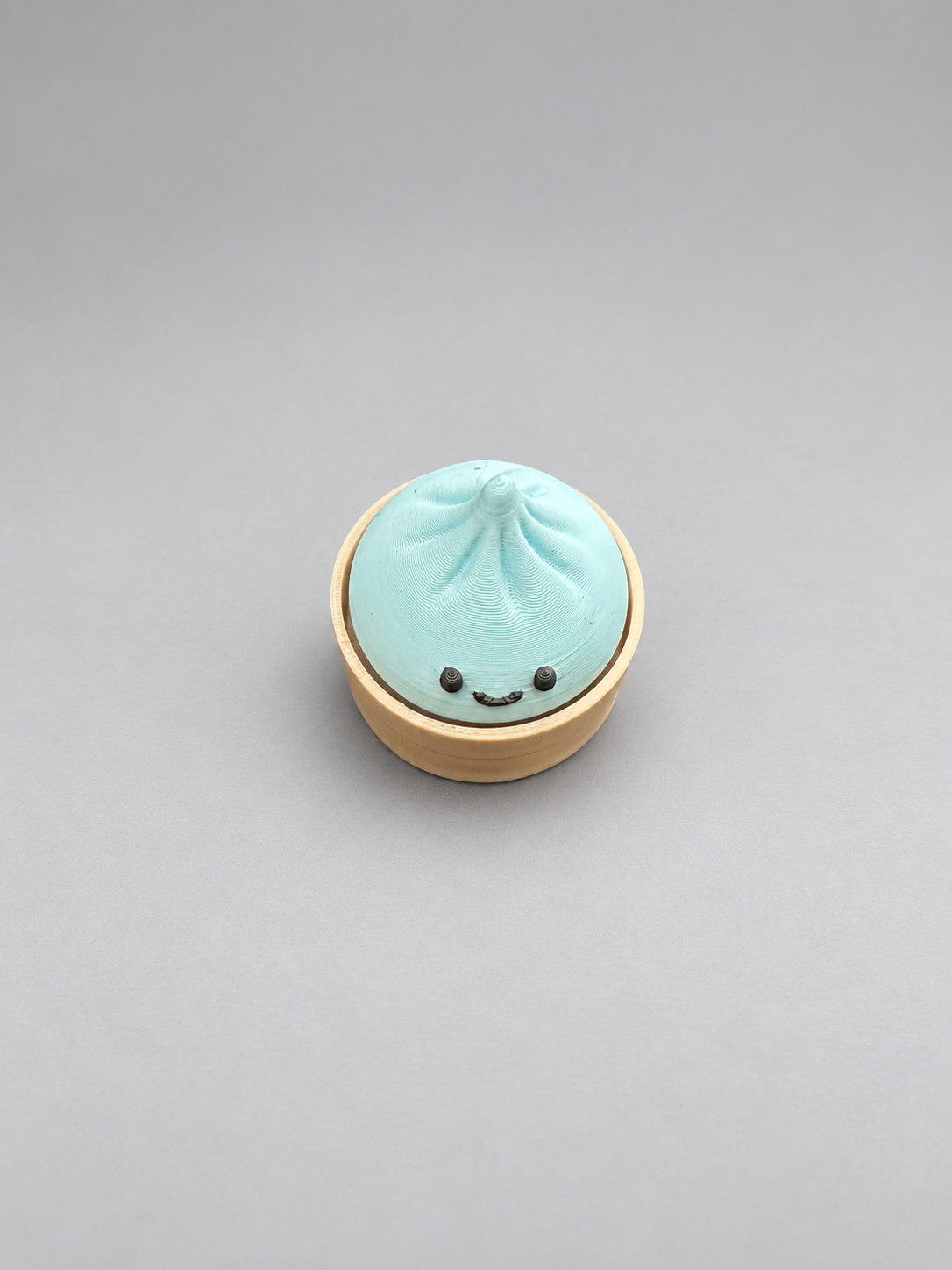 Baby blue dumpling clicker with smiling face and circular base