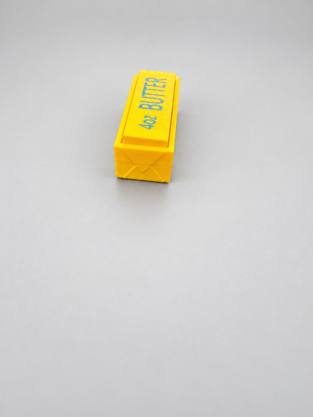 End view of yellow butter clicker showing wrapper-style embossed detail