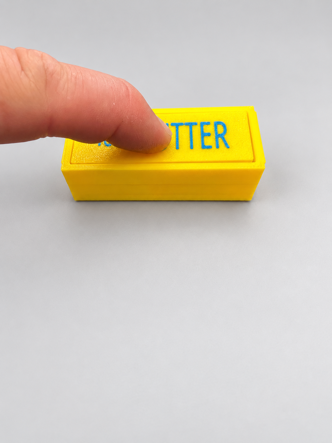 Yellow butter clicker being pressed to demonstrate the clicking mechanism