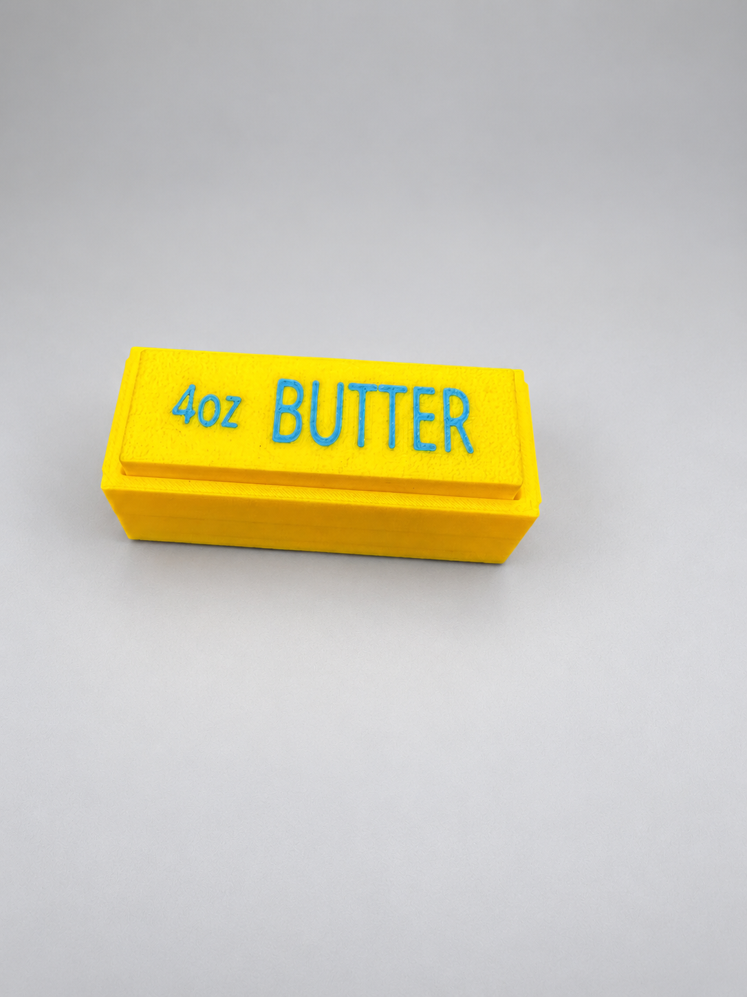Single yellow butter clicker with blue 4oz BUTTER lettering