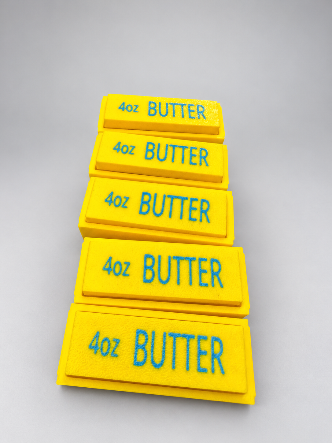 Group of five yellow butter clickers with blue 4oz BUTTER lettering