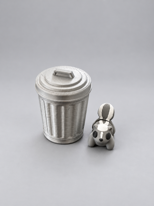 Articulated grey, white and black skunk beside its silver bin with twist-and-lock lid